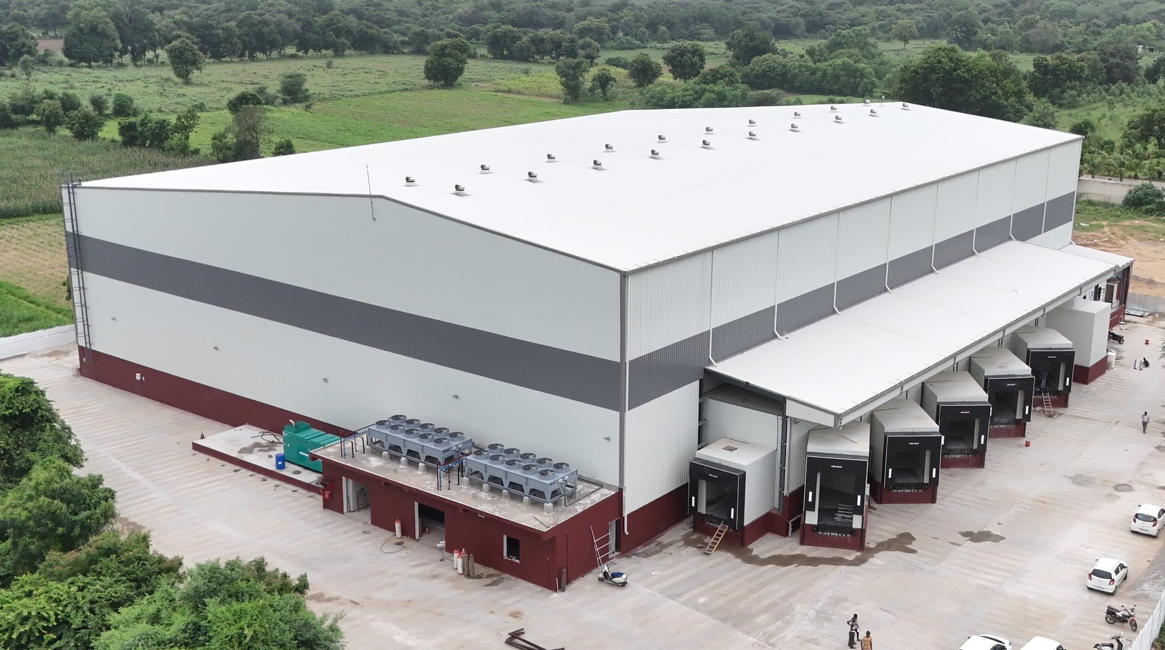 White and grey PEB warehouse with dock shelters, aerial view by AcuFabInfraStructure
