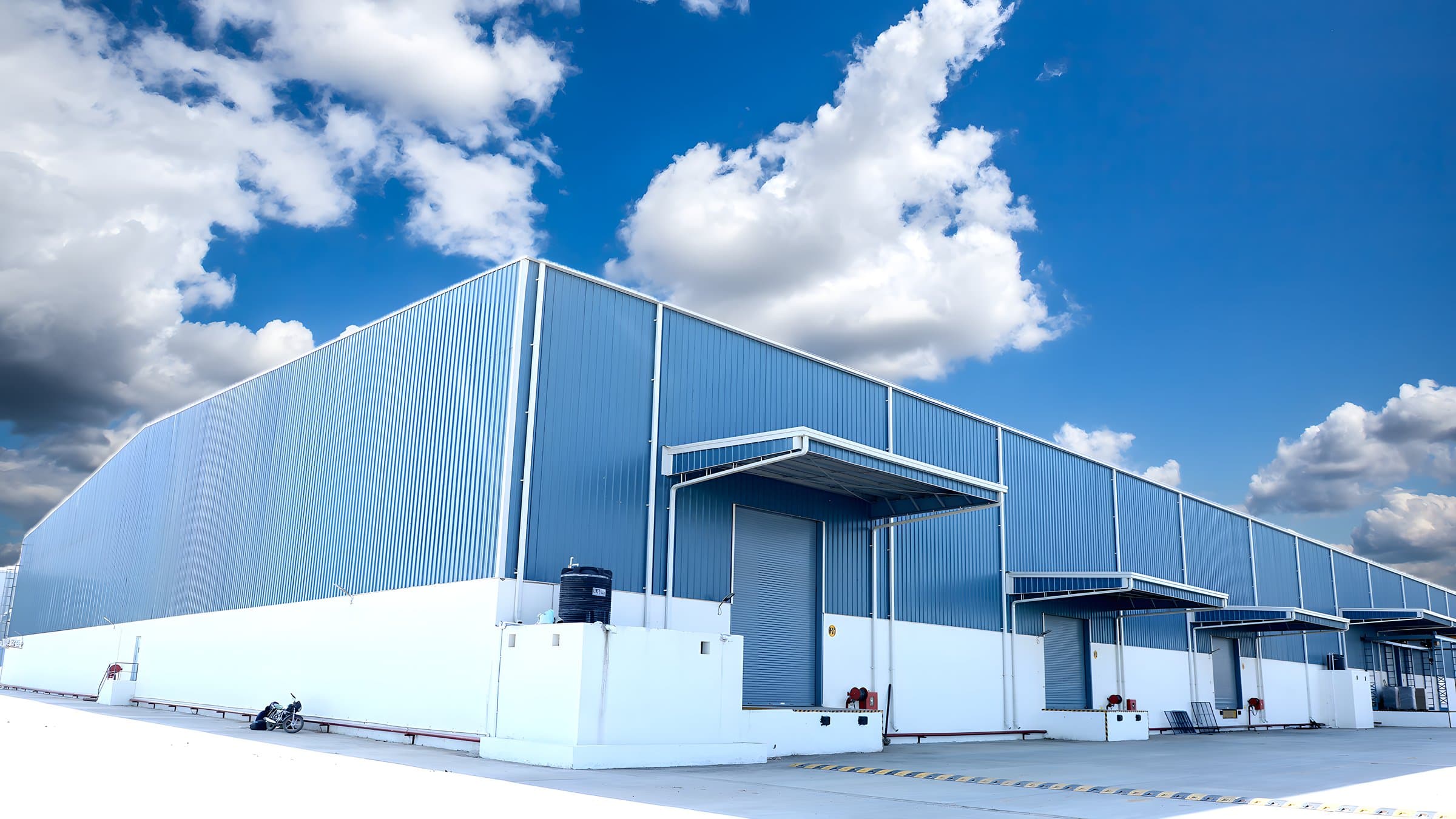 Blue-clad PEB warehouse with loading dock canopies by AcuFabInfraStructure