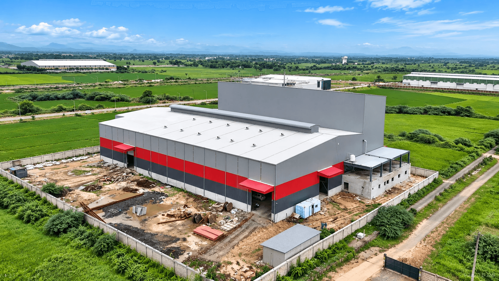 Aerial view of a grey and red clad PEB factory building
