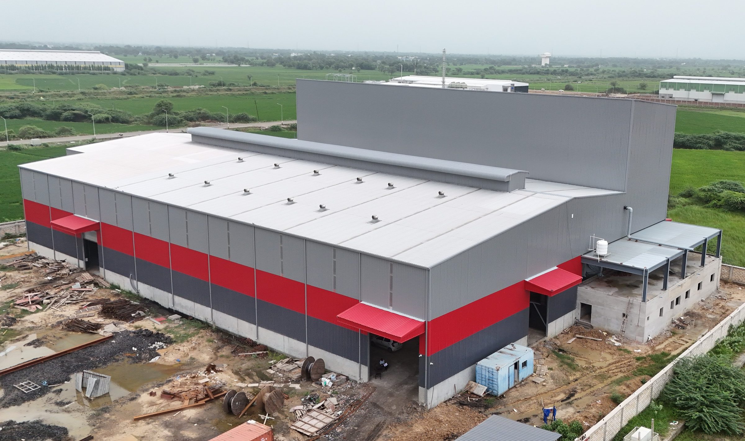 Industrial plant with red and grey cladding by AcuFabInfraStructure, aerial view